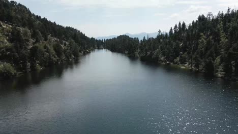 drone advancing through a big lake and descending to approach to the water, in la cerdanya, catalunya 4k