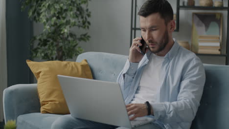 hombre trabajando desde casa en una computadora portátil y una llamada telefónica