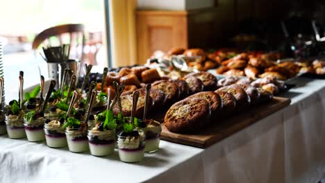 Desserts-in-glass-bowl-and-savory-buns-on-table-with-white-tablecloth,-Czechia