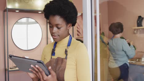 portrait of happy diverse worker and women selling and using tablet in jewellery shop in slow motion