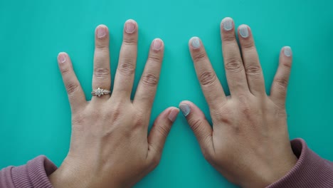 close up of a woman's hands with painted nails on a blue background