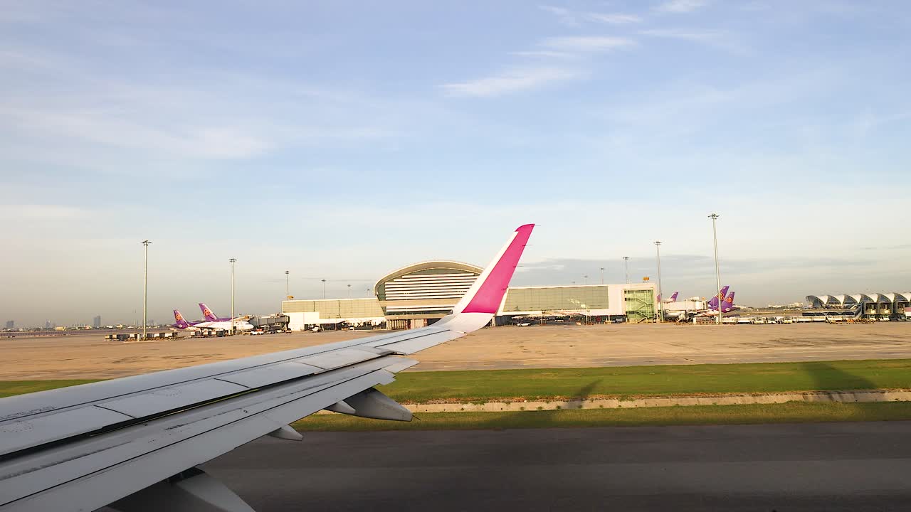 크라비 공항의 활주로에 있는 비행기 택시, 은 하늘 아래의 터미널과 다른 항공기를 보여주는