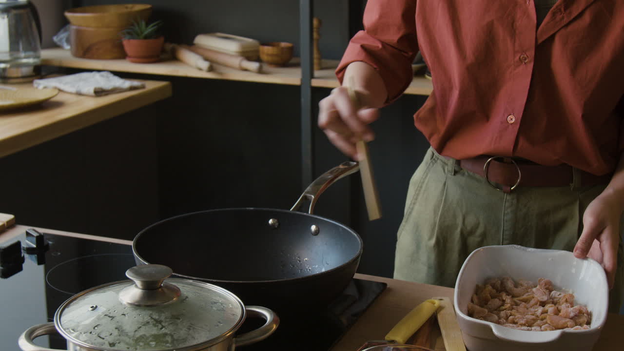 Person Cooking Chicken in a Wok in a Kitchen