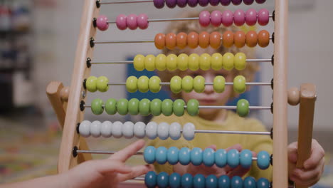 camera focuses on the hands of little kid playing with a panel moving wooden pieces 2