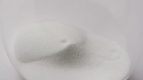 video of close up of hourglass with sand pouring, copy space on white background