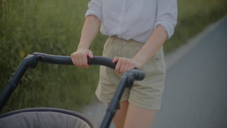 close-up of woman pushing baby stroller at sunset