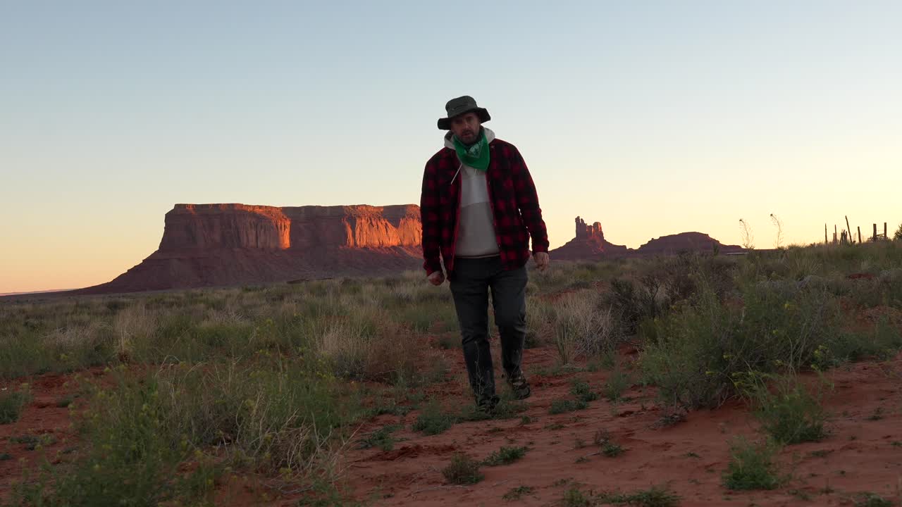 Uomo che cammina in un paesaggio desertico al tramonto nella Monument Valley
