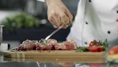 Chef-cooking-raw-steak-at-kitchen-restaurant.-Chef-oiling-pork-fillet