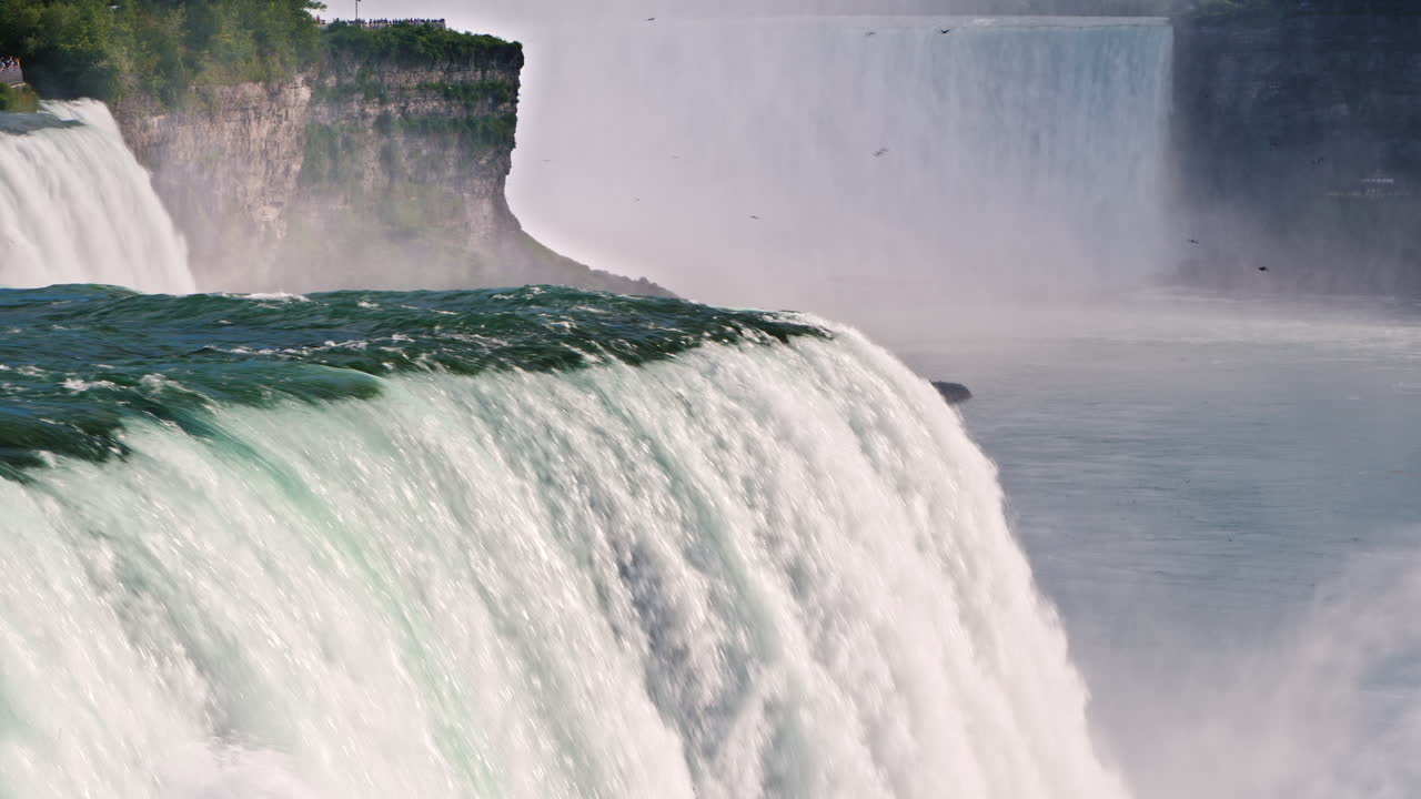 나이아가라 폭포는 배경에서 빠르게 흘러내리고 있습니다. 캐나다 해안에서 폭포를 볼 수 있습니다.