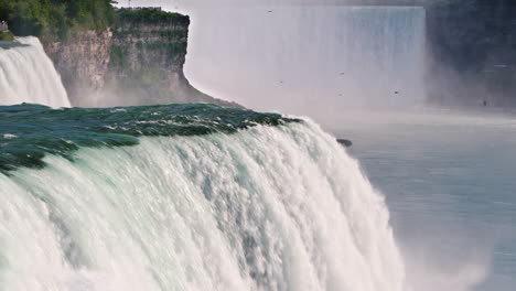 niagara falls is rapidly flowing down in the background you can see a waterfall on the canadian coas