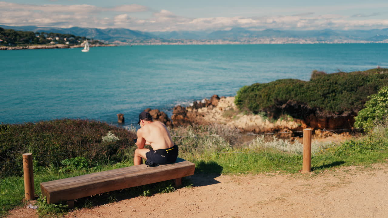 Man sitting on a wooden bench with a view of the sea
