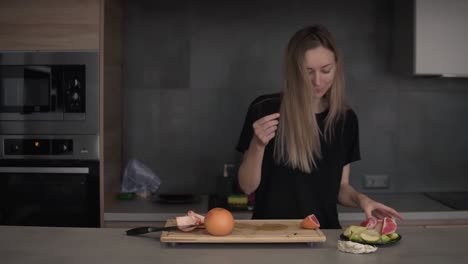 positive woman cleaning grapefruit peel on chopping board at kitchen and dancing