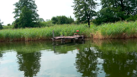 Hierba-Reflejada-En-El-Agua-Transparente-Del-Lago-En-Una-Tierra-Rural-Pacífica