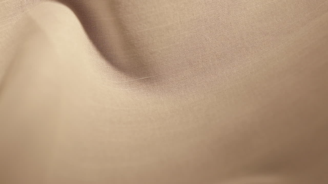 갈색 면화 천 위로 아래로 미끄러지는 단 하나의 금 약혼 반지