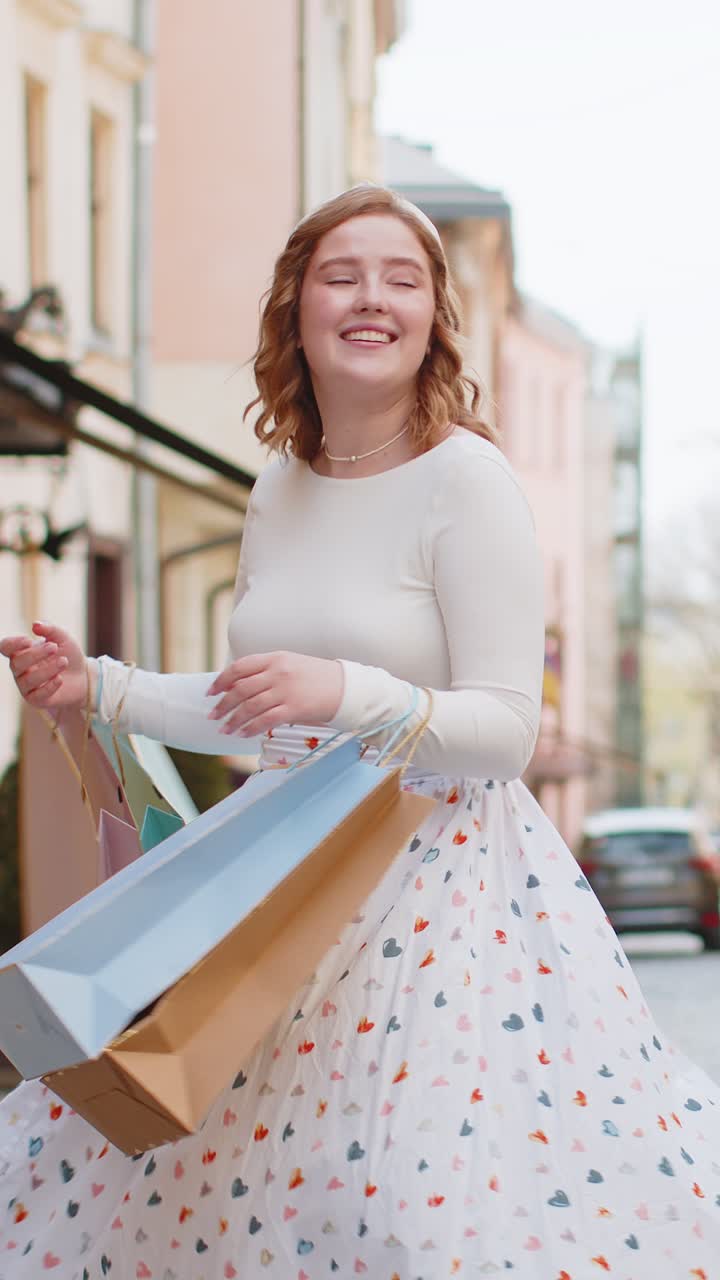 Happy young woman shopaholic consumer after shopping sale with full bags walking in city town street