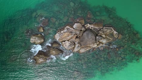 Coral-Reef-Rock-Formations-in-the-Ocean-peaking-out-of-the-Water,-Fishing-Spot-with-vibrant-Aquatic-Marine-Life