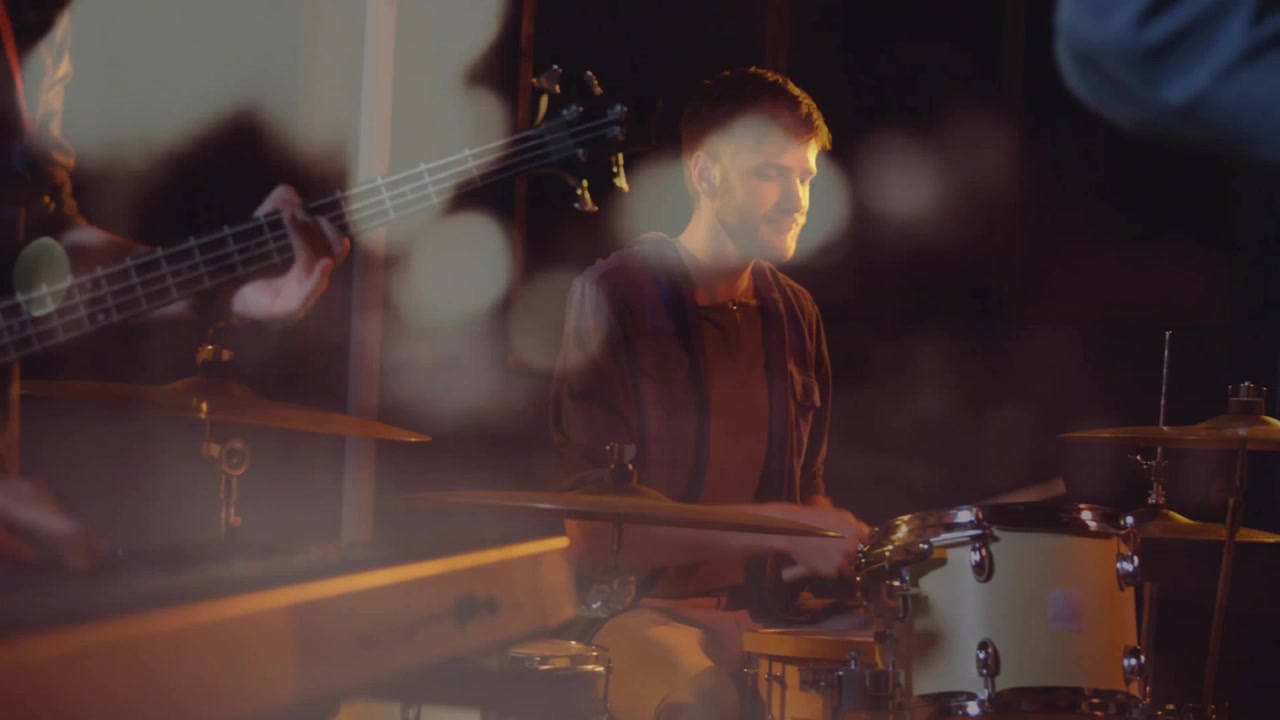 Músico tocando bateria em estúdio de música, mostrando forma de onda animada e sobreposição de gráfico de graves.