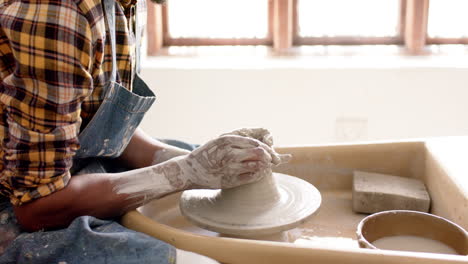 alfarero afroamericano masculino usando la rueda del alfarero en el estudio de cerámica, cámara lenta