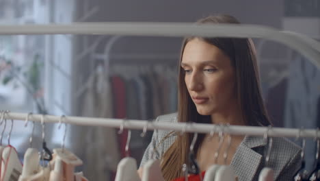 una mujer hermosa elige ropa en una sala de exhibición de ropa de marca.