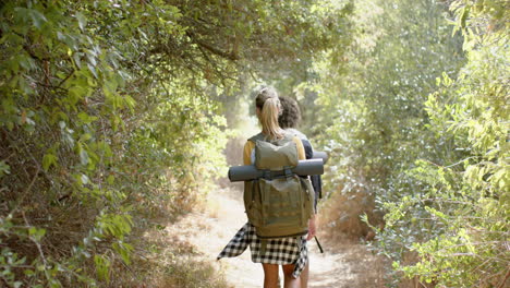una mujer joven con una mochila camina a través de un bosque exuberante