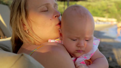 loving mother kissing baby daughter outdoor