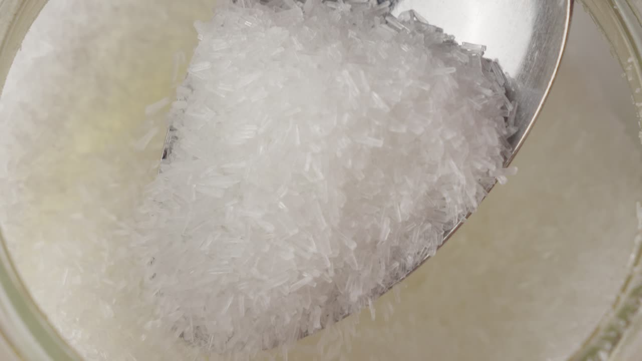 Refined white MSG  covered by steel spoon