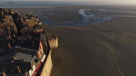 Buildings-and-walls-of-Mont-Saint-Michel-island-during-low-tide,-Normandy-in-France