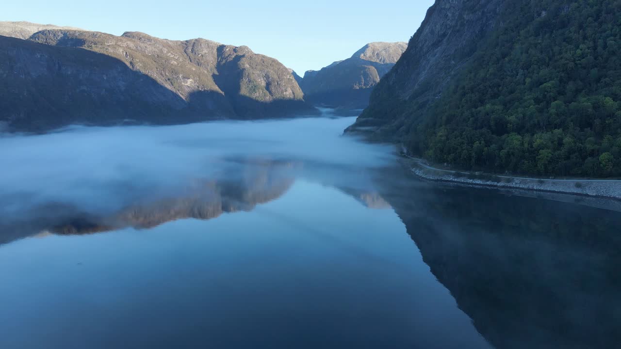 Morning mist and reflection of mountains in Hardanger fjord in Norway. Drone footage