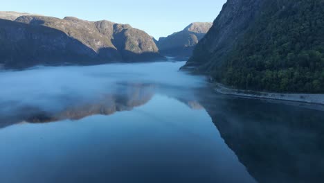 morning mist and reflection of mountains in hardanger fjord in norway. drone footage