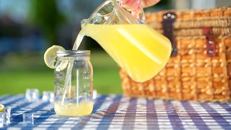 Lemonade-being-poured-from-a-glass-pitcher-into-a-mason-jar