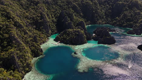 aerial footage of philippines coron island’s tropical beauty, with its dramatic cliffs, pristine beaches, and turquoise waters. rotating drone shot with boats in the harbor.