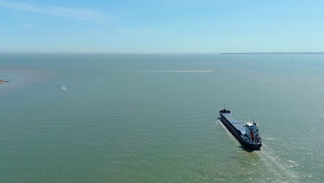 aerial drone view of a large container ship cargo vessel leaving felixstowe port in england heading into the north sea, shipping and export, sunny summer day