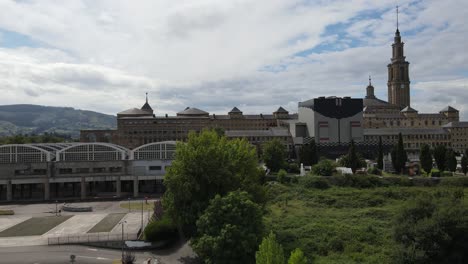 toma aérea ascendente de la laboral en gijón con torres de reloj y montañas en la distancia