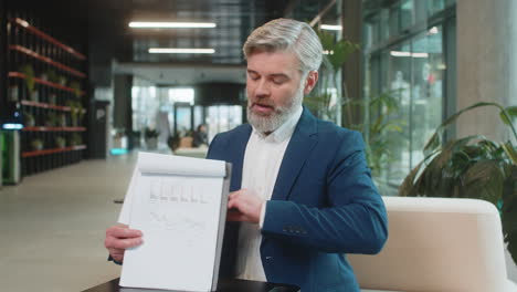 mature businessman making online presentation video call demonstrates reports in office lobby