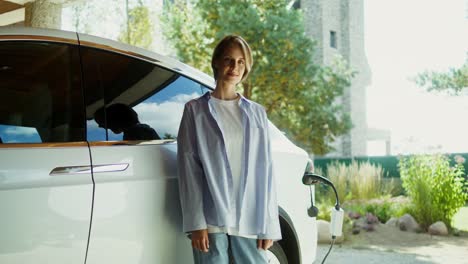 woman standing next to an electric car charging