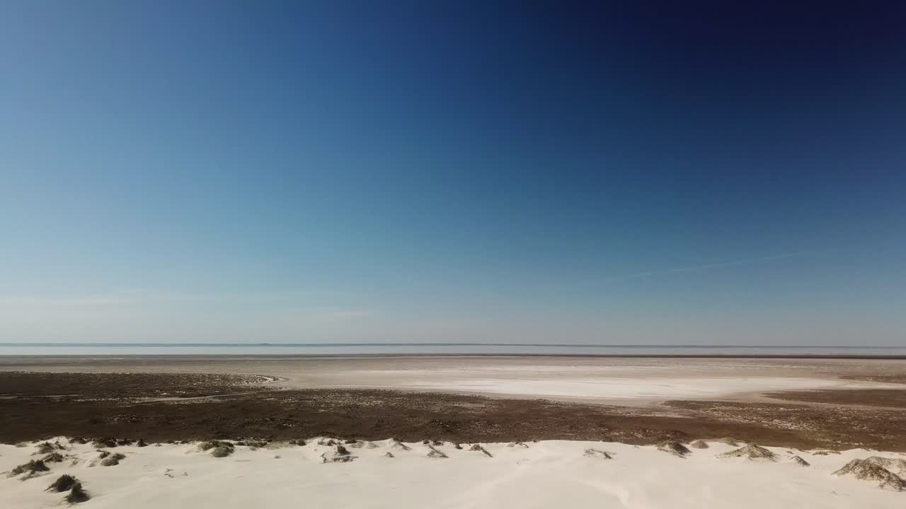 vista aérea de drones de dunas de arena en la isla barrera de la costa del golfo en una tarde soleada, la laguna del estuario es visible en la distancia - isla del padre sur, texas