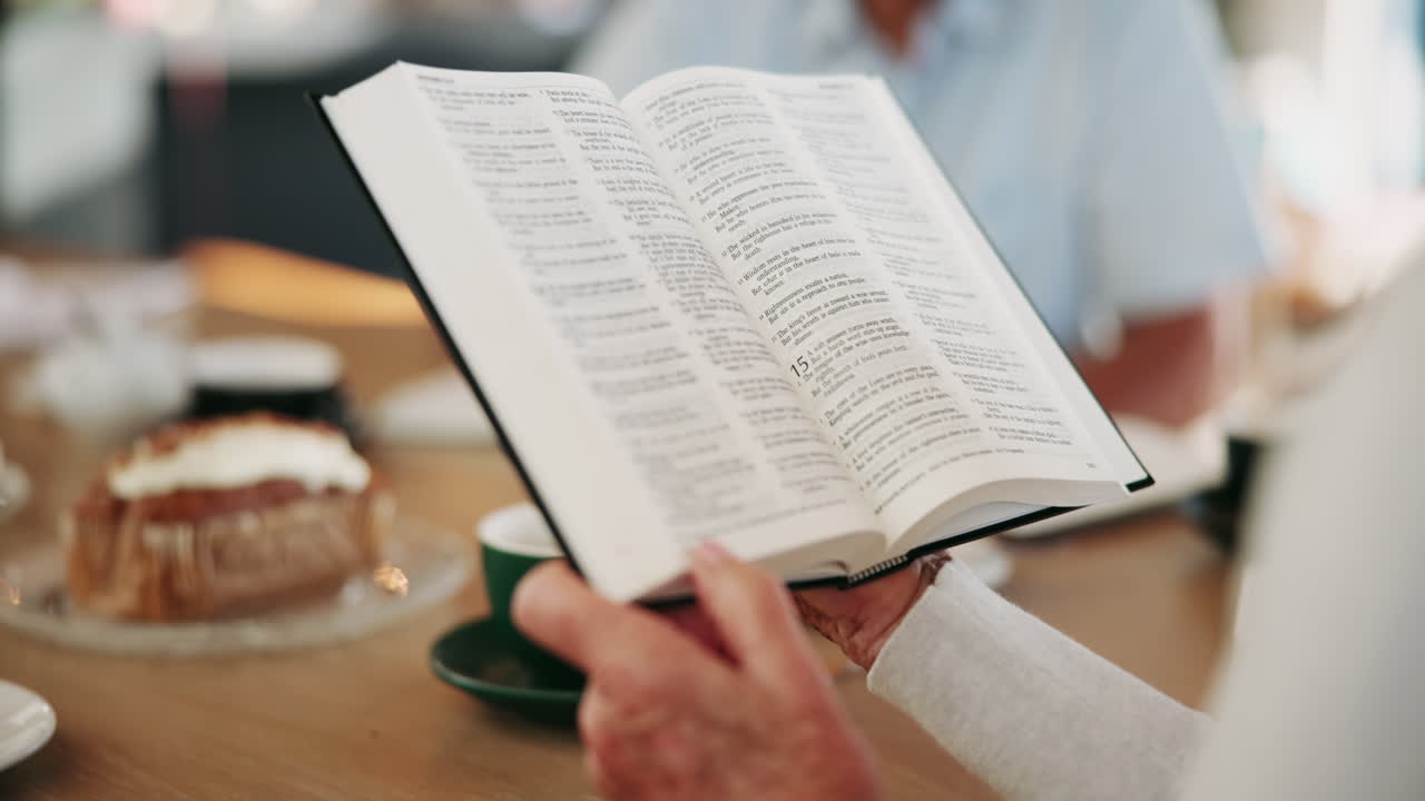 A person reading a book with coffee and cake on a table