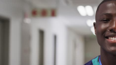 Video-half-face-portrait-of-smiling-african-american-male-medical-worker-in-corridor,-copy-space