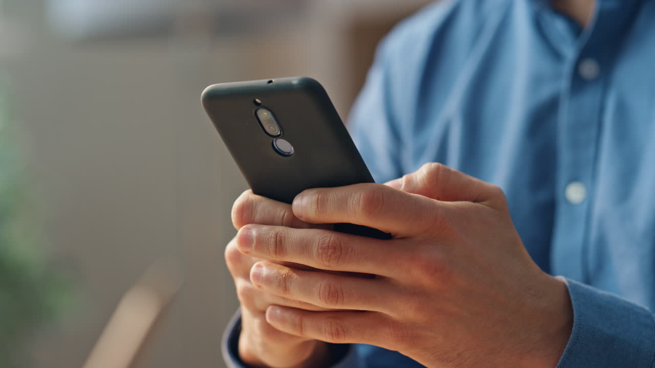 hombre con las manos enviando mensajes por teléfono móvil en la habitación de primer plano. gerente escribiendo teléfono solo