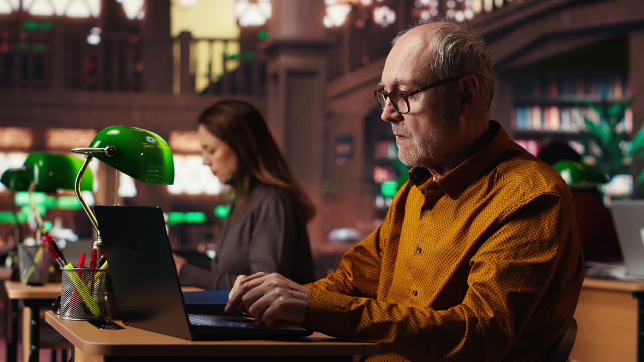 Elderly Man Working on Laptop in Library