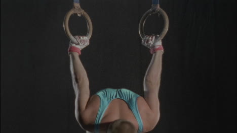 a gymnast jumps up to and grabs the rings