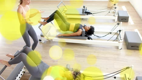 exercising on pilates reformer machines in fitness studio, yellow bubbles animation