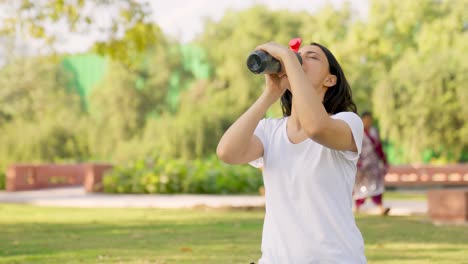 indian girl drinking water from bottle in a park in morning time