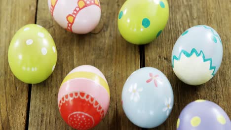 painted easter eggs in the nest on wooden surface