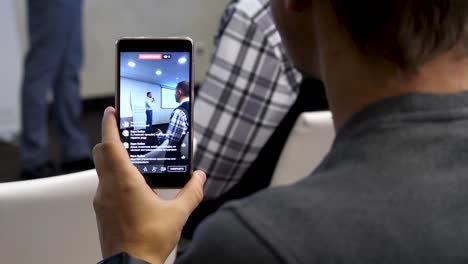 persona que está viendo una transmisión en vivo de una presentación en un teléfono inteligente