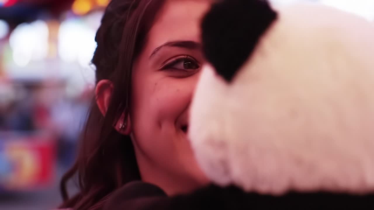 Young Woman Shares Joyful Moment With Giant Panda Plush Toy at a Lively Fairground