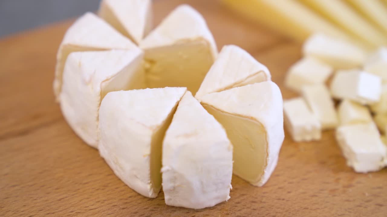 Wedges of Creamy Goat Cheese are Arranged on a Wooden Board, Ready to be Served - Close Up