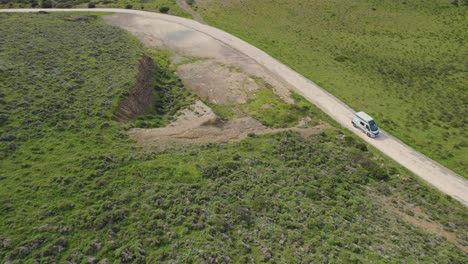 Drone-tracking-camper-van-through-the-mountains-as-it-drives-through-small-roads-in-Bordeira-in-Portugal