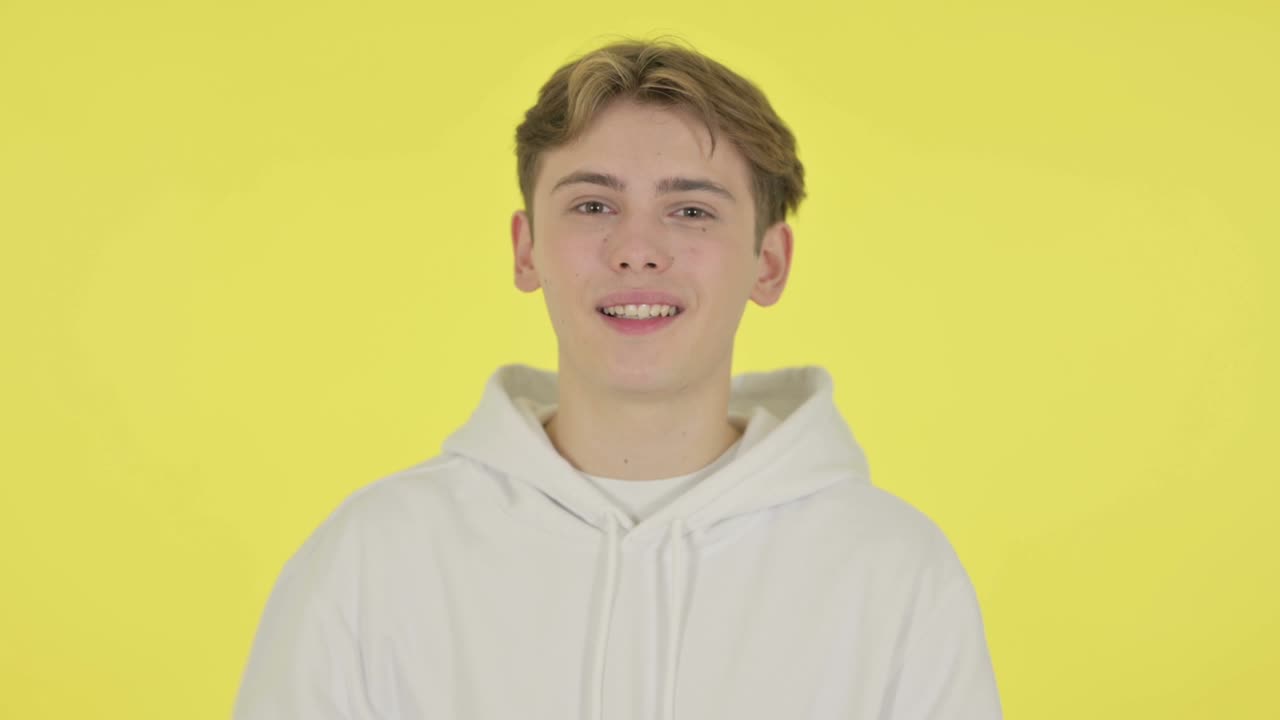 joven apuntando a la cámara, invitando en el fondo amarillo