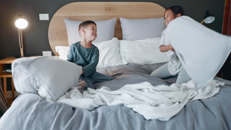 night, happy and children pillow fight on a bed